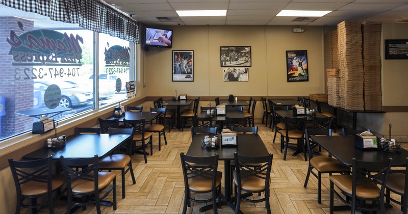 Interior, dining area, tables for four, large shop window, empty stacked pizza boxes