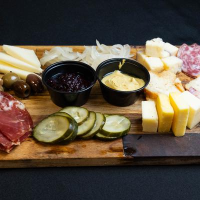 Charcuterie board with assorted cheeses, mustard, blackberry jam, and olives.