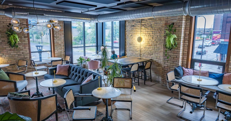 Interior with brick walls, marble tables, woven chairs, and a tufted sofa