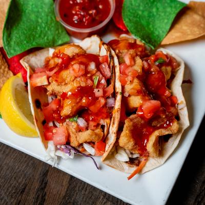 Two fish tacos with Thai chili sauce, pico de gallo, and tortilla chips.