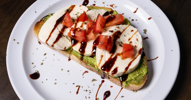 Caprese avocado toast served on a white plate