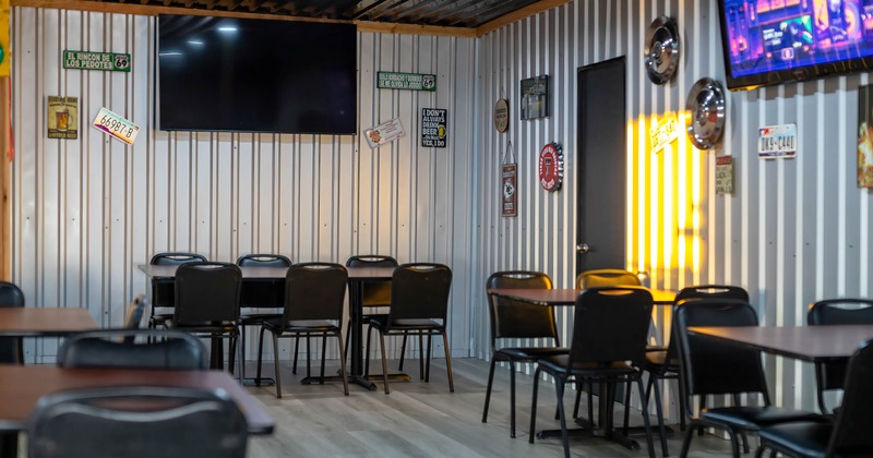 Interior, dining area with metal walls, wooden tables, and black chairs