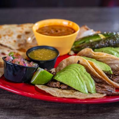 Quesadillas and tacos served with salsa, jalapenos, and soup.