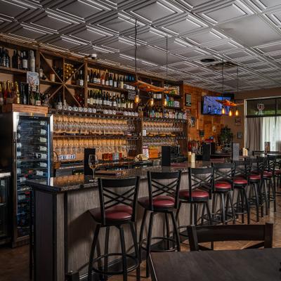 Wine bar interior with stools and bottle shelves.
