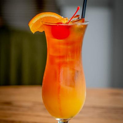 Rum Punch served in a curvy glass on a wooden table.