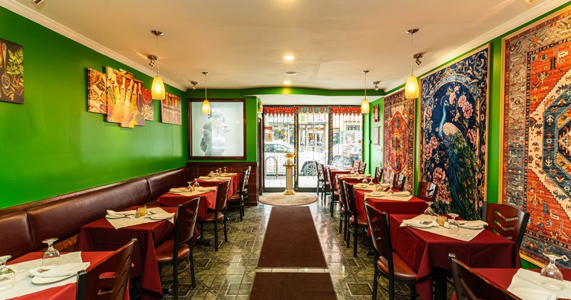 Decorated restaurant interior, green walls, colorful tapestries, red tablecloths, pendant lighting