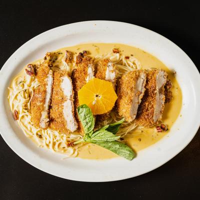Seared breaded chicken with pecans, served over pasta with orange basil cream sauce