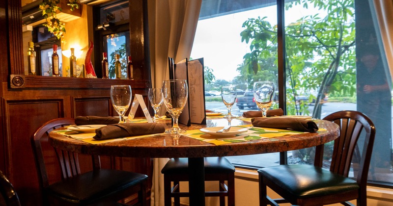 Round table with glasses, plates, napkins, and utensils