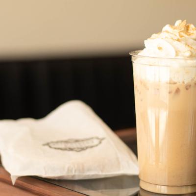 An iced coffee drink topped with whipped cream next to a folded napkin.