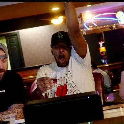 Person cheering while holding a drink in a bar setting.