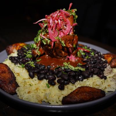 Pork Osso Bucco served with rice, whole black beans and plantains.