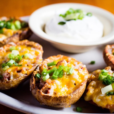 Potato skins topped with melted cheddar cheese, green onion and bacon with sour cream on the side