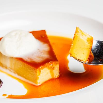 Spoon with a bite of flan in caramele sauce.
