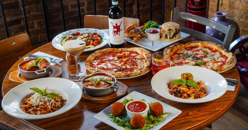 A table with multiple dishes on it including pizza, pasta, and salad