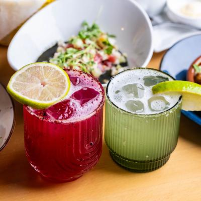 Oaxacan blood and margarita cocktails on a table with food.