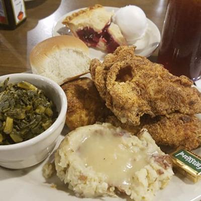 Fried chicken served with mash potatoes and colard greens.