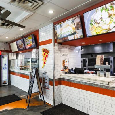 Counter area with white brick walls and digital menu screens displaying food options.
