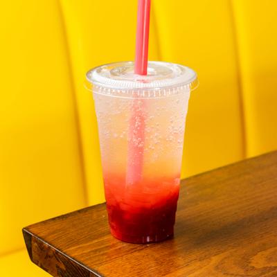 Iced fruity beverage with a red syrup layered at the bottom and a straw.