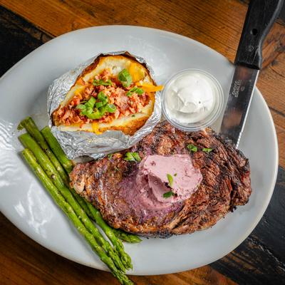 Hereford Beef Hand - Cut Ribeye, served with a house baked potato and sauteed asparagus.