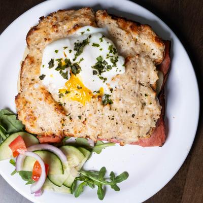 Croque Monsieur topped with poached egg and served with a small salad.