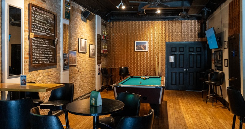 Interior, seating area, pool table in the back, vintage brick walls, hardwood flooring