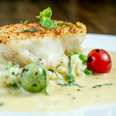 Parmesan Crusted Halibut garnished with cherry tomatoes and herbs, close-up.