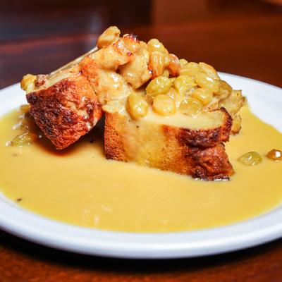 Bread pudding topped with sauce on white plate.
