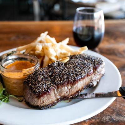 The Tavern Steak, with fries, lettuce and cajun gravy, and red wine, closeup
