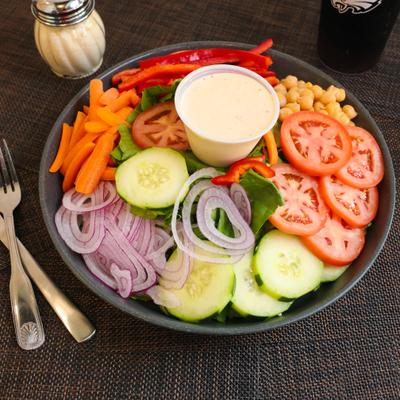 Salad with lettuce, tomatoes, cucumbers, carrots, peppers, onions, chickpeas, and dressing.
