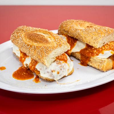 Chicken Parmesan sandwich served on a roll covered in sesame seeds.