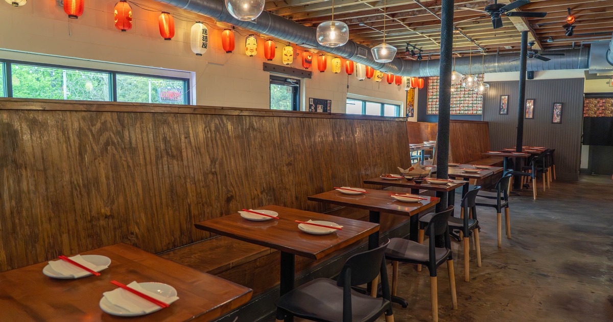 Restaurant interior with wooden tables, red and white lanterns, and pendant lighting