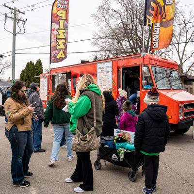 Food truck on parking lot, customer's in front.