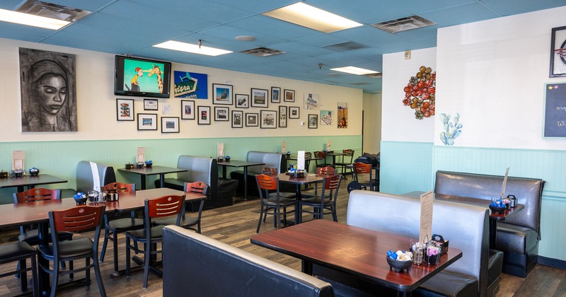 Interior of cozy dining area with dining tables, chairs, and upholstered booths
