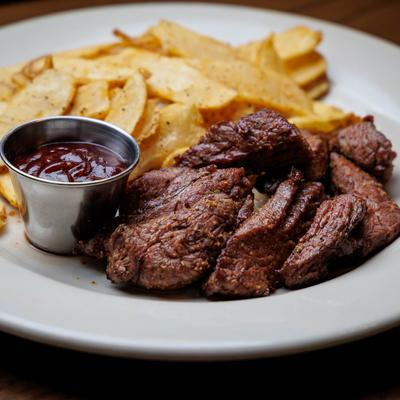 Grilled steak slices with seasoned fries and ketchup.