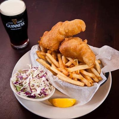 Fish and chips with a side of slaw and lemon, served with a glass of Guinness.