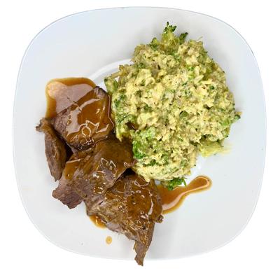 Sliced roast beef with gravy and broccoli mashed potatoes.