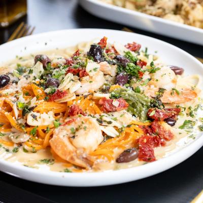 Tri-color pasta featuring sun-dried tomatoes, kalamata olives, shrimp and herbs.