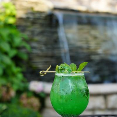 A kiwi and mint cocktail served in an outdoor setting.