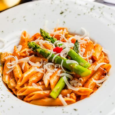 Creamy penne pasta topped with tender asparagus spears, shaved cheese, and herbs.