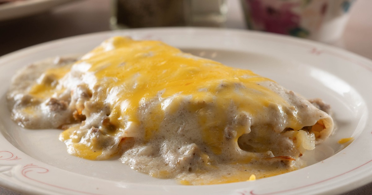 Gravy covered burrito topped with melted yellow cheese