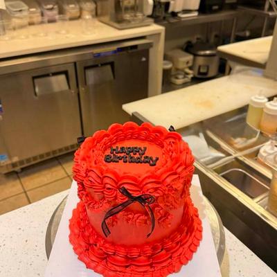 Red vintage birthday cake featuring ruffled buttercream piping and thin black ribbon bows.