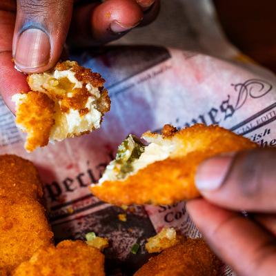 A person holding pieces of fried jalapeno poppers on a plate, close up.