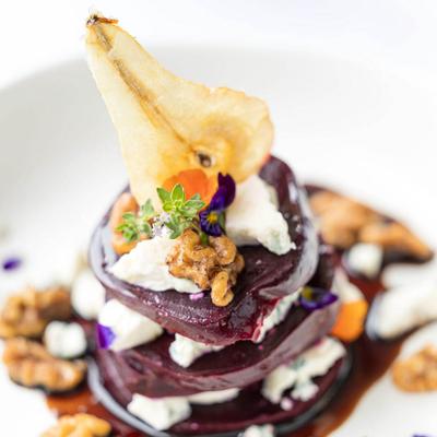 Stacked gourmet beet salad with blue cheese, candied walnuts, and dried pear.