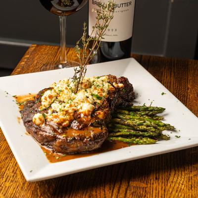 Grilled steak topped with blue cheese, served with asparagus and red wine.