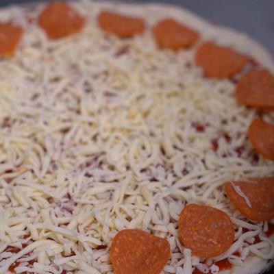 Unbaked cheese and pepperoni pizza.