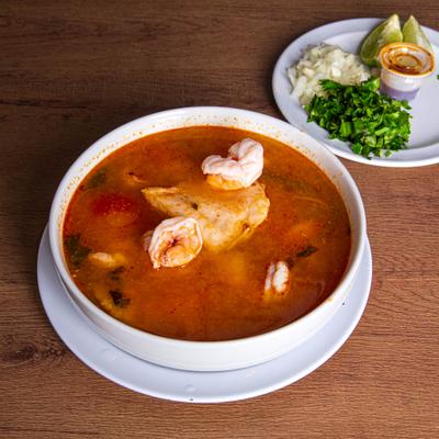 Shrimp, octopus, and fish soup served with chopped onions, cilantro, and lime wedges.