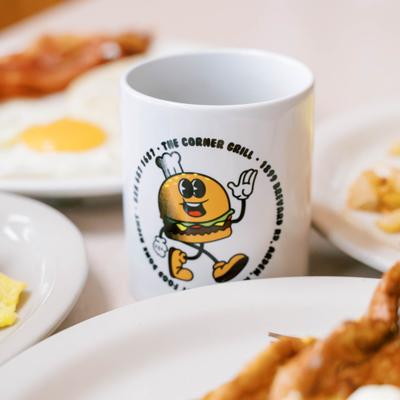Branded coffee mug alongside breakfast dishes.