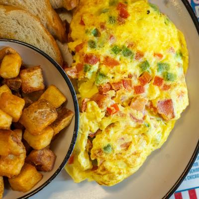 Vegetable omelet with home fries and toasted bread on a plate.