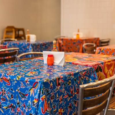 Dining room with tables featuring vibrant colorful tablecloths and condiments.