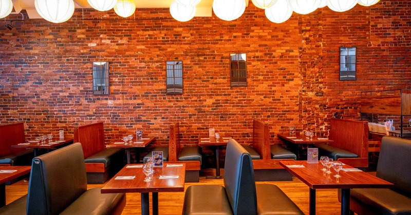 Restaurant interior with brick wall, booth seating, and overhead paper lanterns